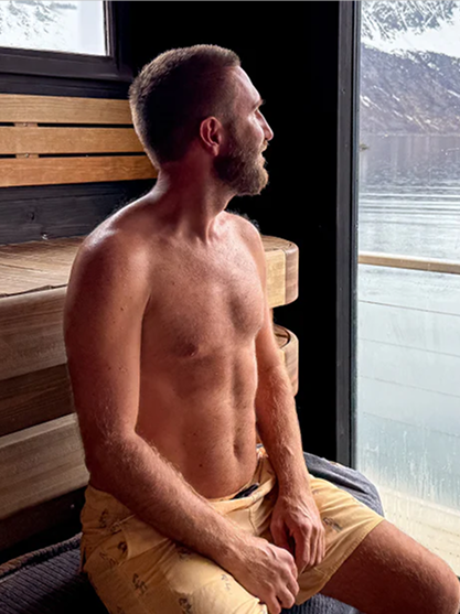 Man looking out the window of his outdoor sauna